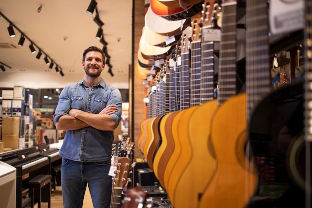 Ritratto di giovane musicista di talento in piedi nel negozio di musica da un'ampia collezione di strumenti per chitarra.