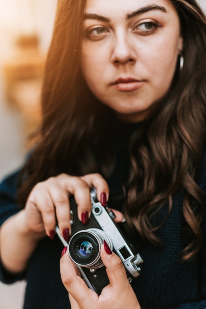 Ritratto di giovane ragazza adulta con fotocamera vintage all'aperto