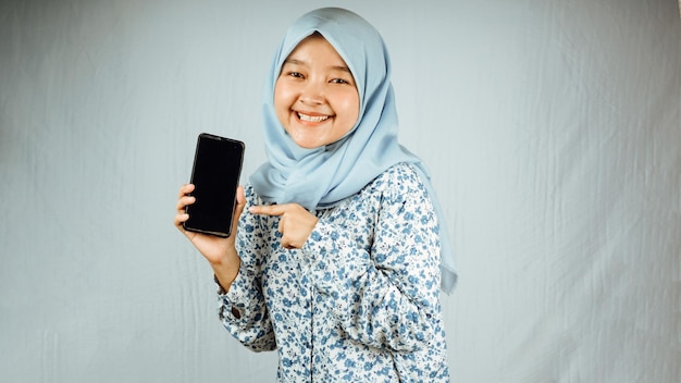 Ritratto di giovane ragazza asiatica attraente del hijab che tiene telefono cellulare