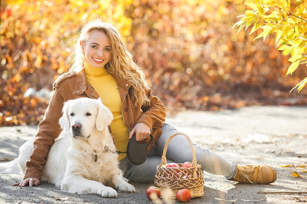 Ritratto di giovane ragazza bionda attraente con cane. Proprietario dell'animale domestico. Golden retriever e il suo proprietario in autunno.