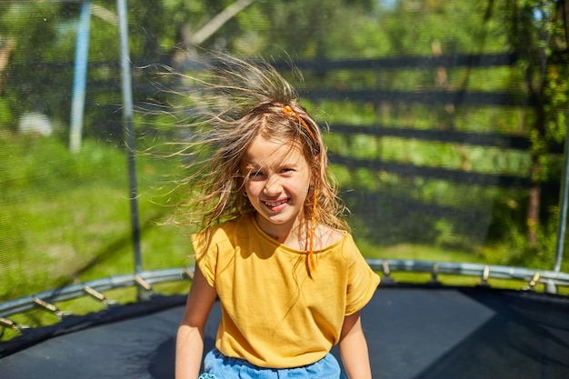 Ritratto di giovane ragazza con capelli elettrificati sul trampolino all'aperto, nel cortile