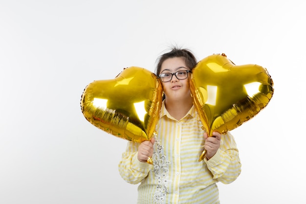 Ritratto di giovane ragazza con una sindrome di Down in possesso di palloni ad aria a forma di cuore