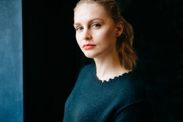 Ritratto di giovane ragazza modello. Espressioni del viso di donna elegante elegante alla moda. Bella bionda con gli occhi adorabili gentili che posano per la macchina fotografica. Silhoutte della bambina isolata sul nero. Emozioni, stato d'animo