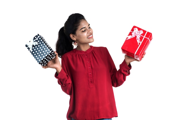 Ritratto di giovane ragazza sorridente felice azienda e posa con scatole regalo su uno sfondo bianco.