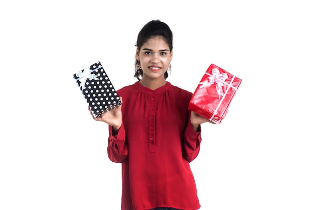 Ritratto di giovane ragazza sorridente felice azienda e posa con scatole regalo su uno sfondo bianco.