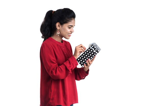 Ritratto di giovane ragazza sorridente felice azienda e posa con scatole regalo su uno sfondo bianco.