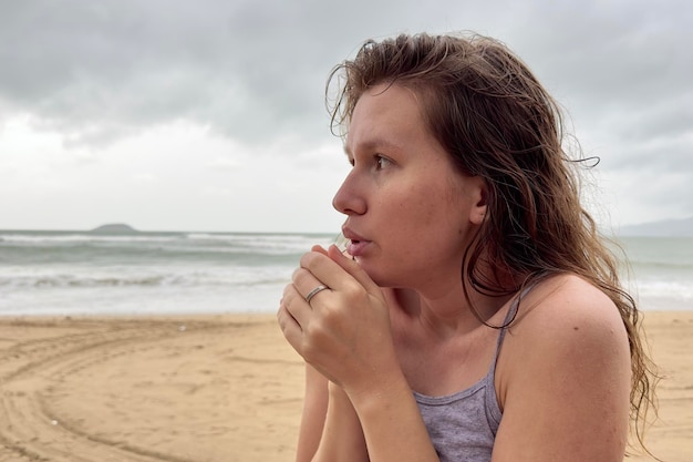 Ritratto di giovane ragazza tremante congelata depressa infelice che trema dal freddo triste donna sconvolta sul maltempo della spiaggia del mare durante le vacanze estive