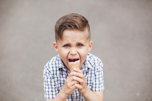 Ritratto di giovane ragazzo che mangia il gelato all'aperto