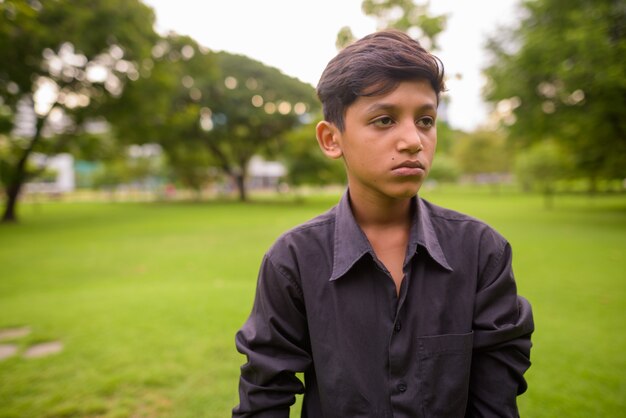 Ritratto di giovane ragazzo indiano rilassante presso il parco
