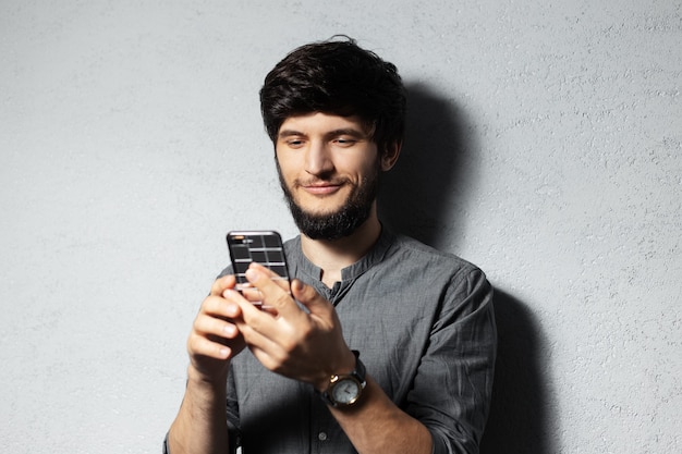 Ritratto di giovane ragazzo sicuro di sé utilizzando smartphone.