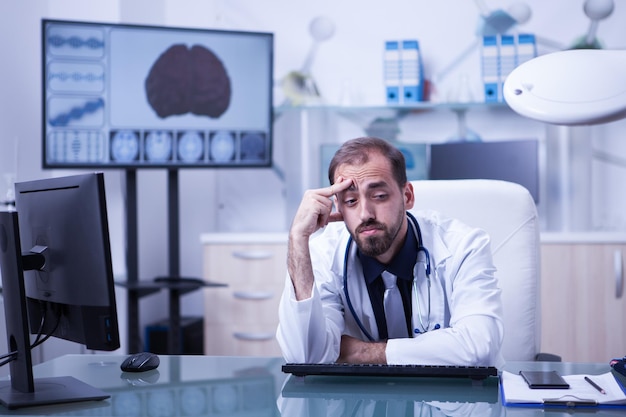 Ritratto di giovane scienziato sovraccarico di lavoro nel laboratorio dell'ospedale. Dottore che ha mal di testa dopo una lunga giornata in ospedale.