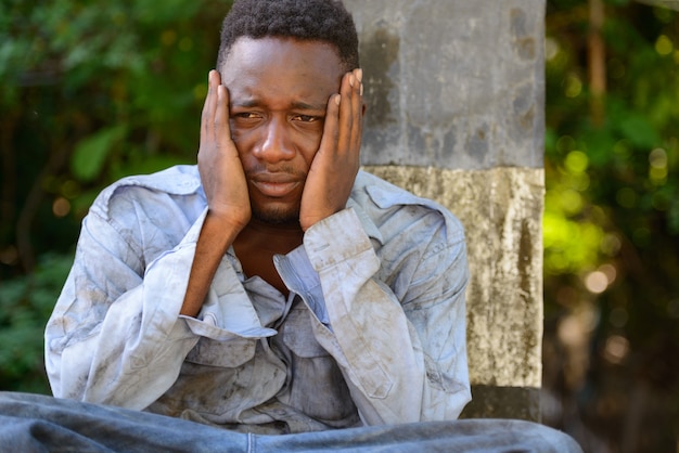 Ritratto di giovane senzatetto uomo africano sul ponte nelle strade all'aperto