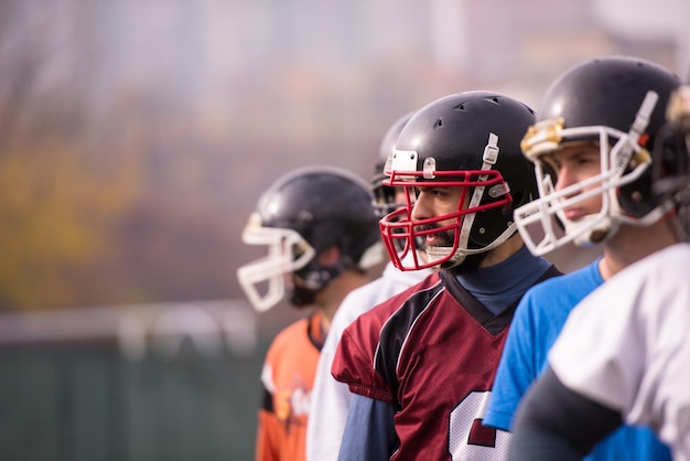 ritratto di giovane squadra di football americano in piedi uno dietro l'altro sul campo