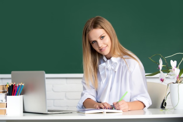 Ritratto di giovane studente di college sorridente che scrive che studia in classe