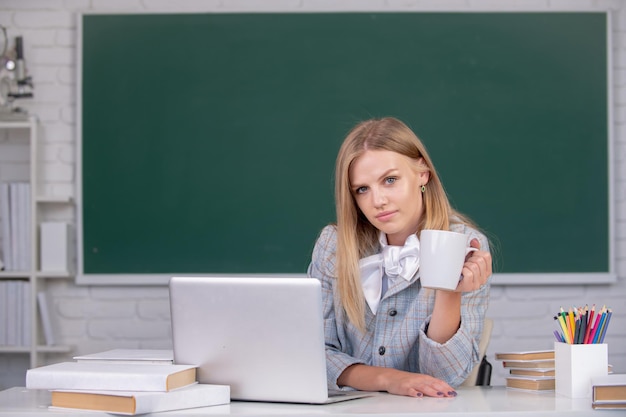 Ritratto di giovane studentessa carina e attraente che beve caffè o tè all'università o al liceo ...