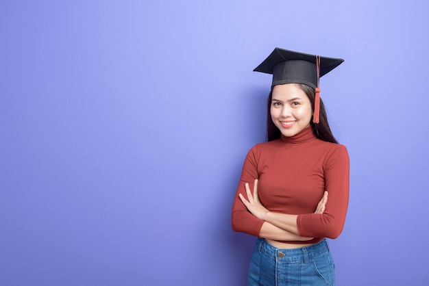 Ritratto di giovane studentessa universitaria con cappello di laurea su viola