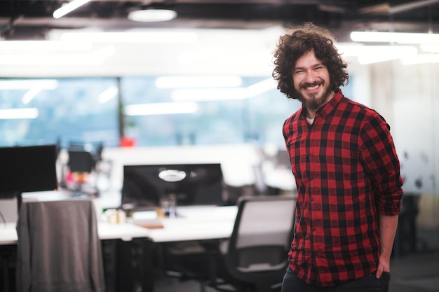 Ritratto di giovane sviluppatore di software maschio di successo sorridente in piedi in un moderno ufficio di avvio