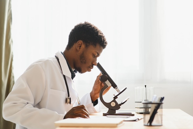 Ritratto di giovane uomo afro-americano che lavora in laboratorio preparando campioni di prova per la ricerca, copia dello spazio