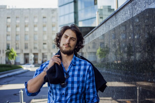 Ritratto di giovane uomo alla moda bello sulla strada. Con la felpa con cappuccio sulla spalla