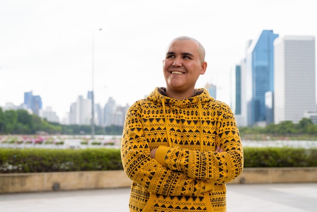 Ritratto di giovane uomo asiatico calvo contro la vista della città al parco a Bangkok, Tailandia