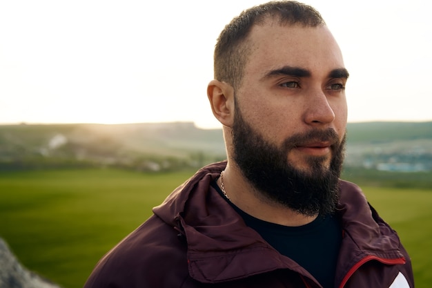 Ritratto di giovane uomo barbuto all'aperto in montagna