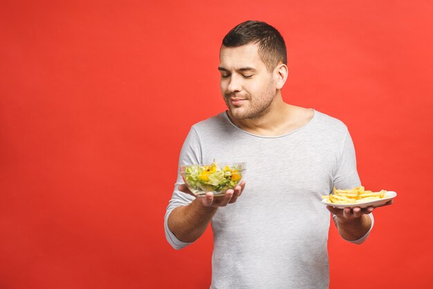 Ritratto di giovane uomo bello assetati di cibo spazzatura invece di mangiare cibo sano