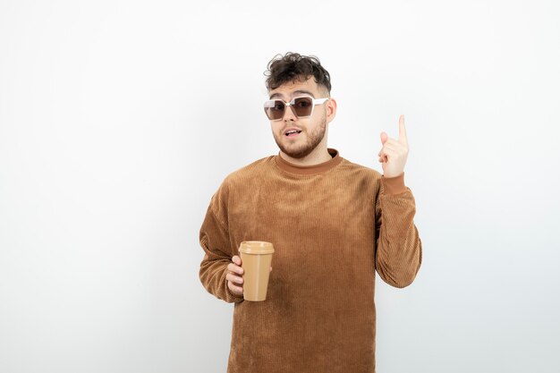 Ritratto di giovane uomo bello che tiene tazza di caffè.