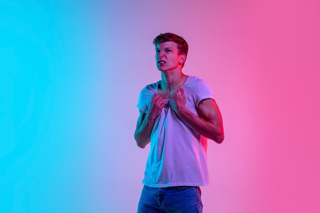 Ritratto di giovane uomo caucasico su studio sfumato blu-rosa in luce al neon