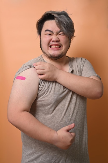 Ritratto di giovane uomo che mostra il braccio con un bendaggio dopo la vaccinazione Vaccinazione e immunizzazione