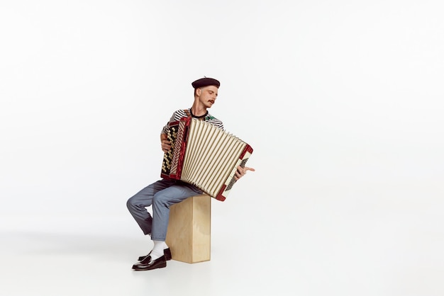 Ritratto di giovane uomo che suona la fisarmonica in posa isolato su sfondo bianco per studio musica positiva