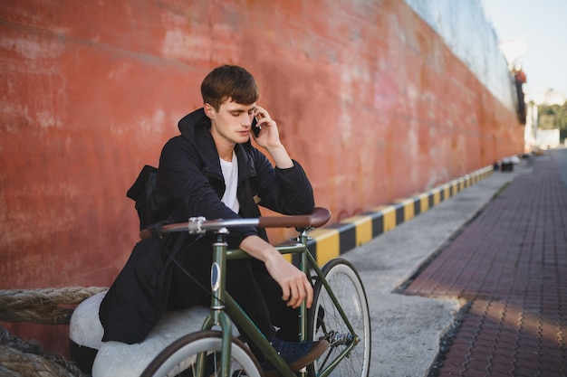 Ritratto di giovane uomo con capelli castani in piedi con la bicicletta