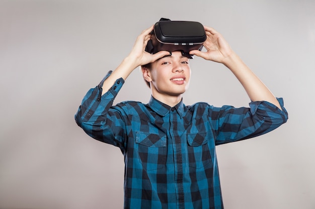 Ritratto di giovane uomo con cuffie da realtà virtuale. indoor, isolato su sfondo grigio.