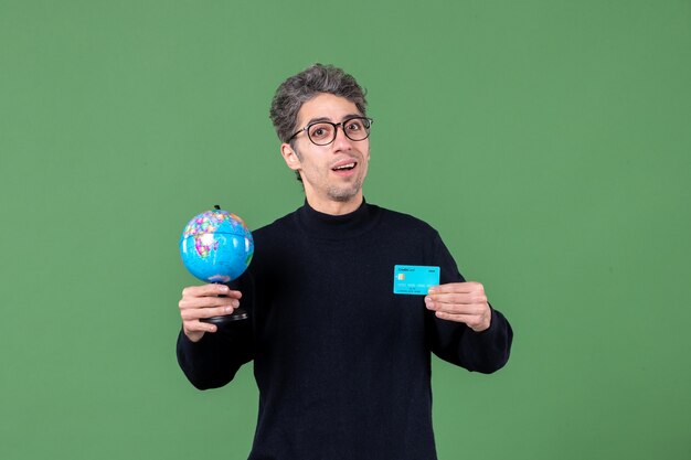 ritratto di giovane uomo con globo terrestre e carta di credito sfondo verde insegnante di banca natura male