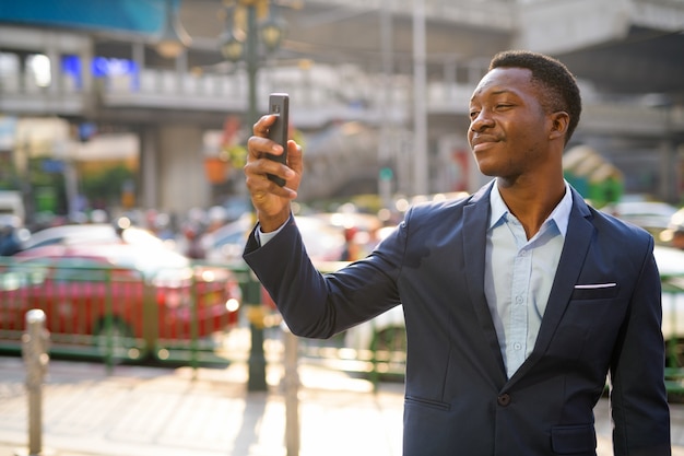 Ritratto di giovane uomo d'affari africano bello esplorare le strade della città di Bangkok