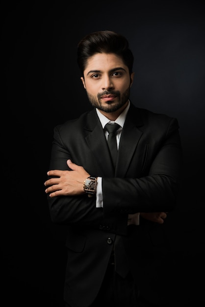 Ritratto di giovane uomo d'affari indiano barbuto su sfondo nero, illuminazione lunatica