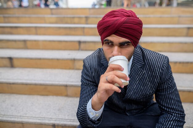 Ritratto di giovane uomo d'affari indiano bello Sikh che indossa turbante mentre esplora la città di Bangkok, Thailandia