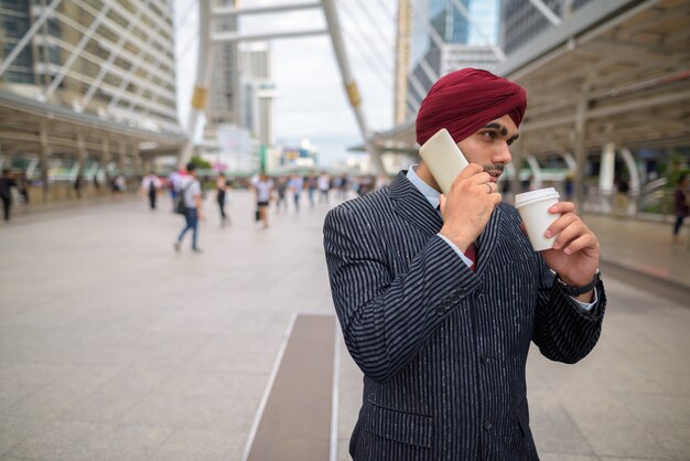 Ritratto di giovane uomo d'affari indiano bello Sikh che indossa turbante mentre esplora la città di Bangkok, Thailandia