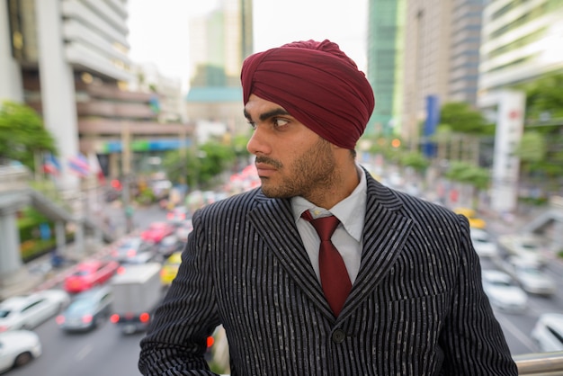 Ritratto di giovane uomo d'affari indiano bello Sikh che indossa turbante mentre esplora la città di Bangkok, Thailandia