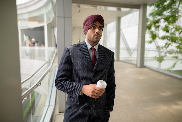 Ritratto di giovane uomo d'affari indiano bello Sikh che indossa turbante mentre esplora la città di Bangkok, Thailandia