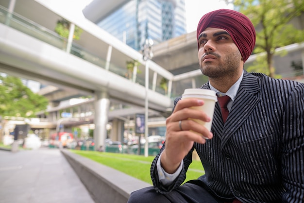 Ritratto di giovane uomo d'affari indiano bello Sikh che indossa turbante mentre esplora la città di Bangkok, Thailandia