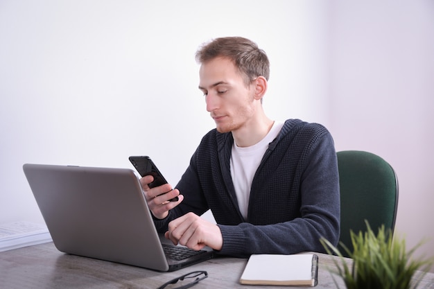 Ritratto di giovane uomo d'affari seduto alla sua scrivania computer portatile tecnologia in ufficio. Internet marketing, finanza, concetto di affari