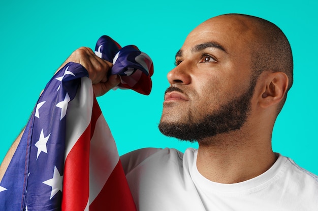 Ritratto di giovane uomo dalla carnagione scura che tiene con orgoglio la bandiera USA