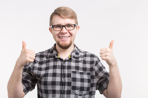 Ritratto di giovane uomo felice in bicchieri con il pollice in alto che indossa la camicia a scacchi.