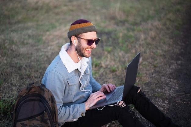 Ritratto di giovane uomo hipster utilizzando laptop all'aperto