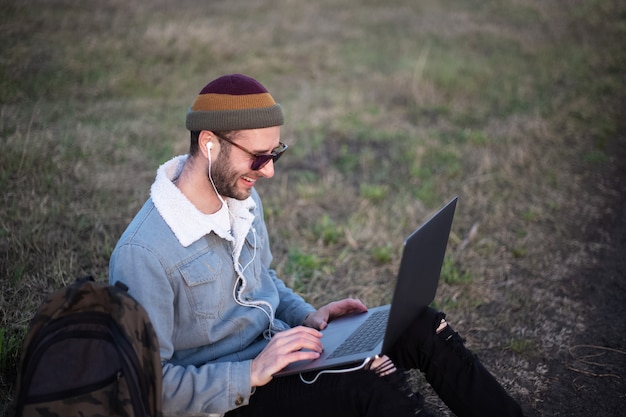 Ritratto di giovane uomo hipster utilizzando laptop all'aperto