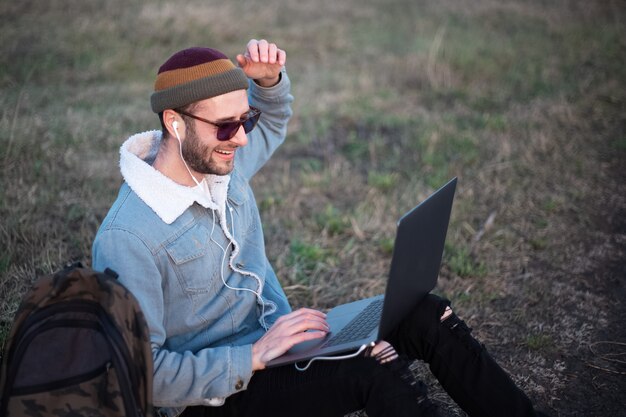 Ritratto di giovane uomo hipster utilizzando laptop all'aperto