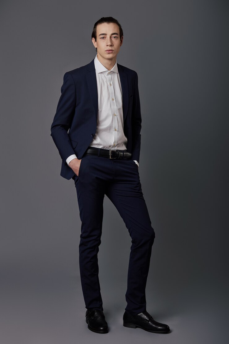 Ritratto di giovane uomo in abito blu scuro sul muro grigio