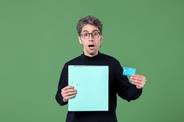 ritratto di giovane uomo in possesso di documento e carta di credito su sfondo verde natura insegnante maschio banca soldi