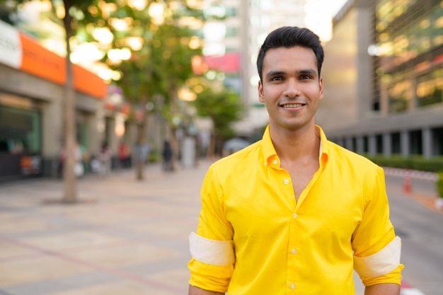 Ritratto di giovane uomo indiano bello nelle strade della città all'aperto