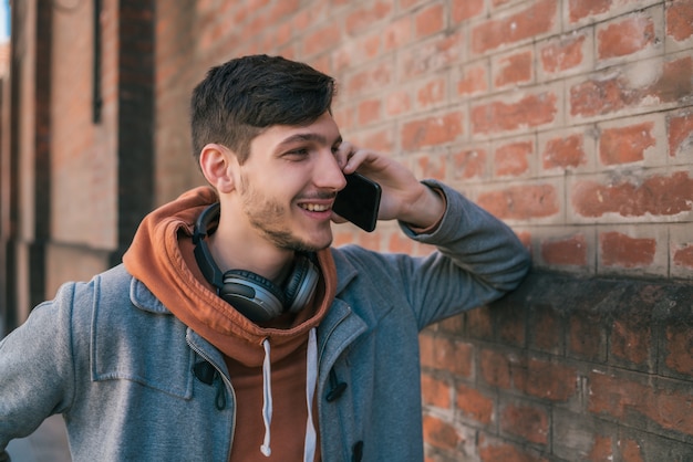 Ritratto di giovane uomo latino parlando al telefono all'aperto in strada.